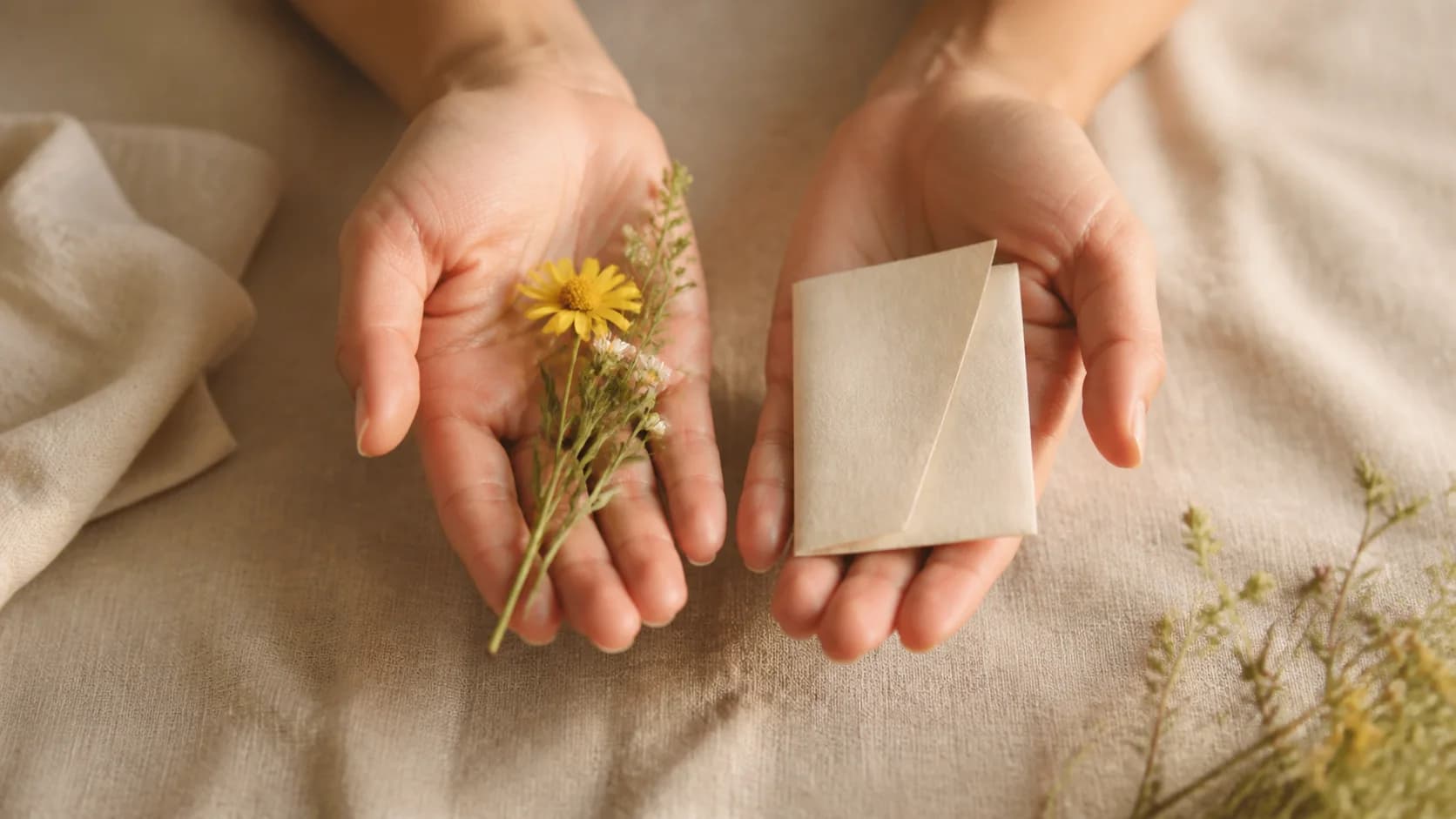 Mãos oferecendo pequenas flores e um bilhete dobrado em branco